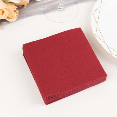 Stack of burgundy paper napkins on a table setting.