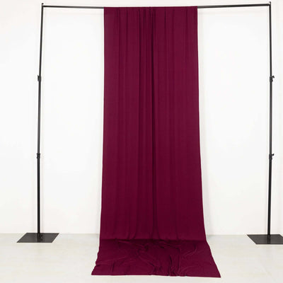 Burgundy fabric draped on a black stand against a plain background