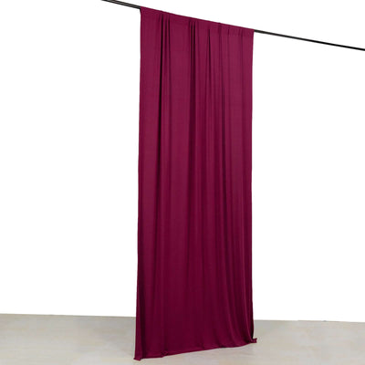 Burgundy fabric drape hanging from a rod against a plain backdrop