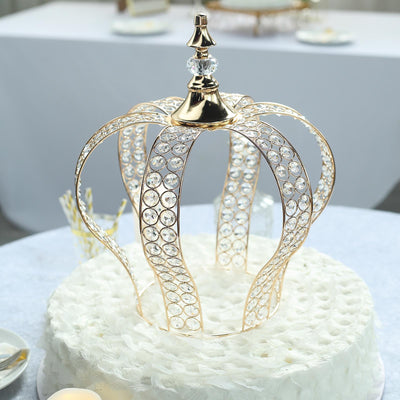 Gold crown cake topper with crystal accents on a white cake.
