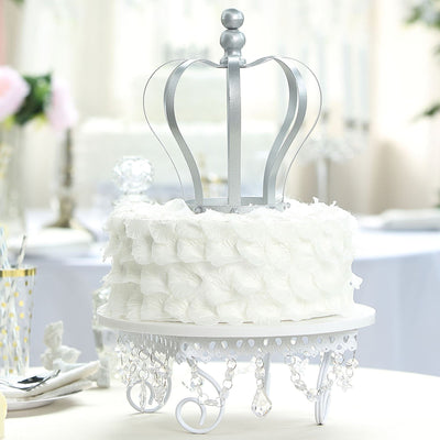 Elegant white crown cake topper with floral detail on a decorative stand.