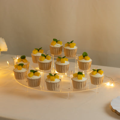 Mango and mint topped cupcakes on a clear display stand with soft lighting.