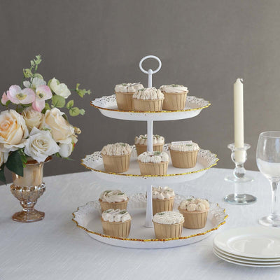 Three-tiered cupcake stand with decorated cupcakes, floral arrangement, and elegant table setting.