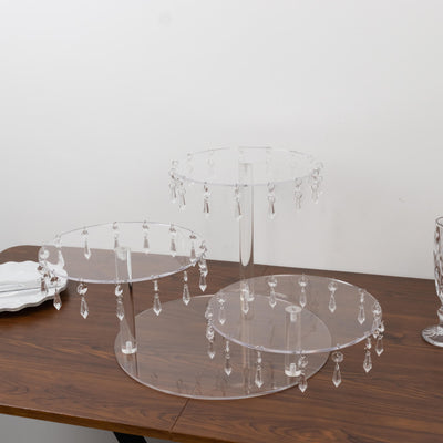 Acrylic cake stands with hanging crystals on a wooden table.