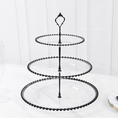Three-tiered black serving tray with beaded edge on a white background.