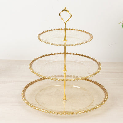 Three-tier glass serving stand with gold accents and bead detailing.
