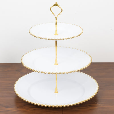Three-tiered serving platter with gold trim and handle.