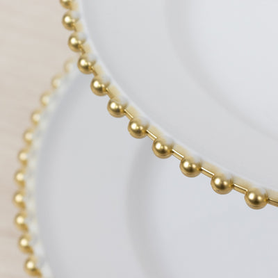 Elegant white plates with gold bead trim, stacked for display.