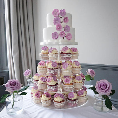 Elegant cupcake display with pink floral decorations on a tiered stand.
