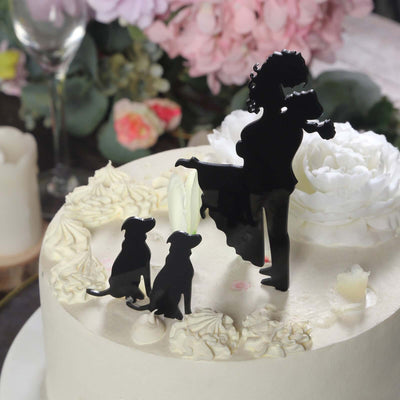 Black silhouette cake topper with a woman and two dogs on a decorated cake.