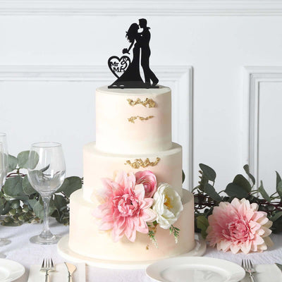 Wedding cake with floral accents and a couple cake topper.
