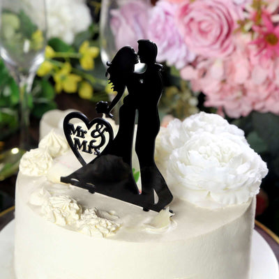 Black wedding cake topper with couple silhouette and "Mr & Mrs" text.