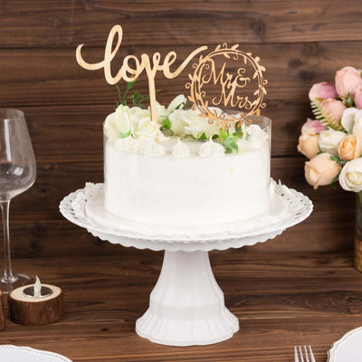 Wedding cake with "Love" and "Mr & Mrs" toppers on a decorative stand.