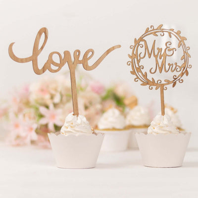 Wooden cupcake toppers "love" and "Mr & Mrs" on decorated desserts.