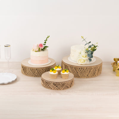Decorative cake stands with floral arrangements and desserts on a light wooden table.