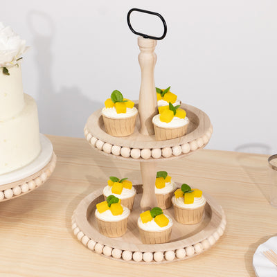 Two-tier wooden dessert stand with cupcakes and mint leaves.