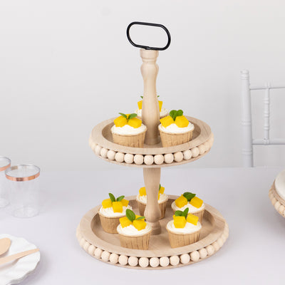 Two-tier wooden cupcake stand with cupcakes topped with mango and mint leaves.