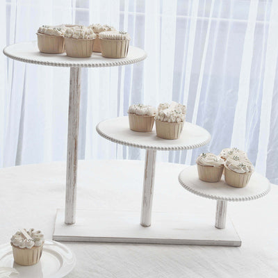 Three-tiered cupcake stand with decorated cupcakes on a light backdrop.