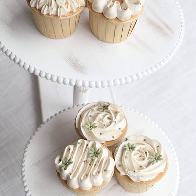 Decorative cupcakes with cream frosting and green accents on a tiered stand.