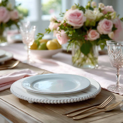 Elegant table setting with white plates and pink floral centerpiece.