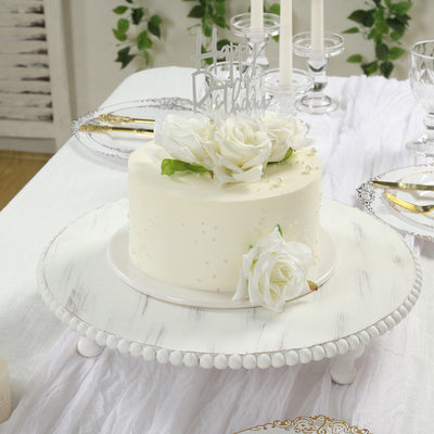 Elegant white birthday cake adorned with roses on a decorative cake stand.