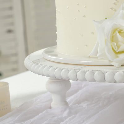 Elegant white cake adorned with a rose on a decorative stand.