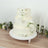 Elegant three-tier wedding cake adorned with white roses and greenery.