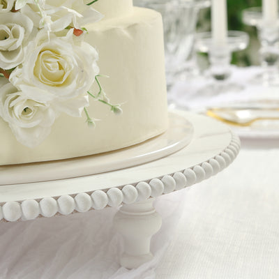 Wedding cake with white roses on a decorative cake stand.