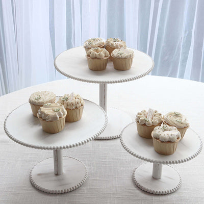 Assorted decorative cupcakes on tiered white stands.