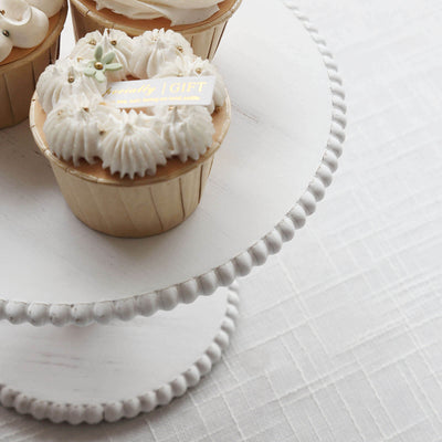 Decorative cupcakes on a tiered cake stand with white frosting and embellishments.