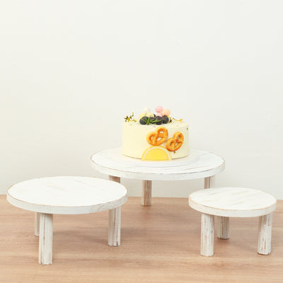 Decorative cake on a white wooden stand with two smaller stands underneath.