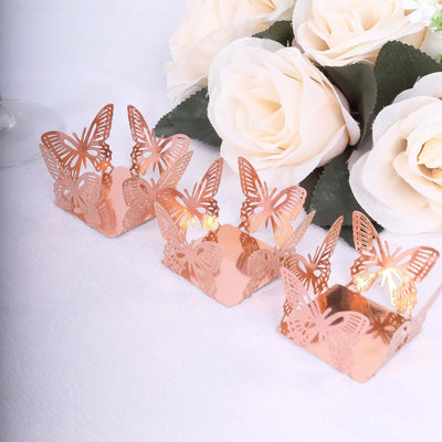 Rose gold butterfly candle holders with floral backdrop.