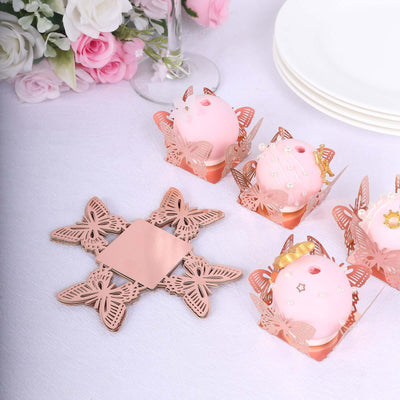 Rose gold butterfly cupcake holders with pink cupcakes on a white tablecloth.