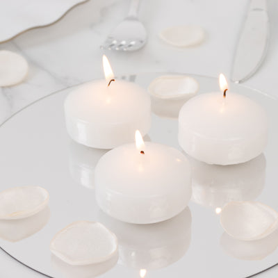 Three white candles lit on a mirrored surface with decorative petals.