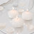 Three white candles lit on a mirrored surface with decorative petals.