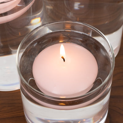 Pink floating candle in water with a gentle flame.