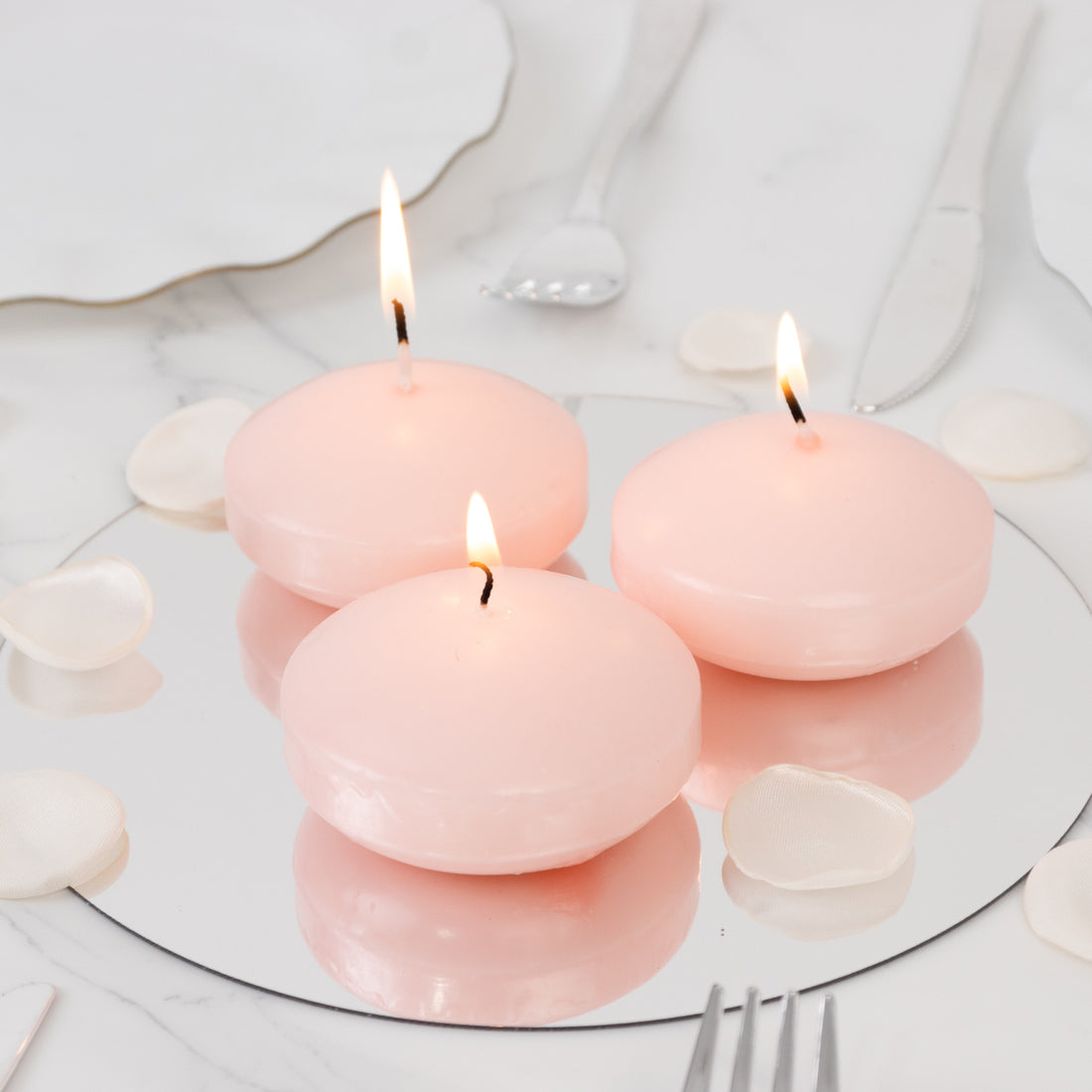 Pink floating candles on a mirrored surface with rose petals.