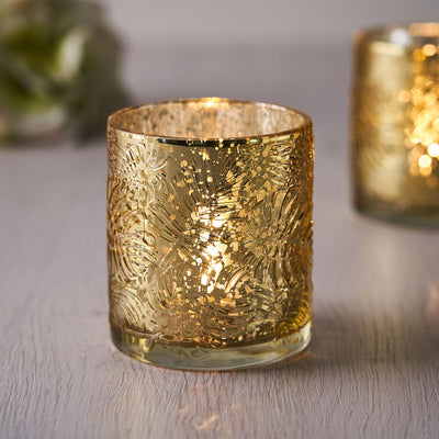 Gold decorative candle holder with intricate design and warm glow.