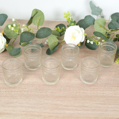 Set of six vintage glass candle holders on a wooden surface.