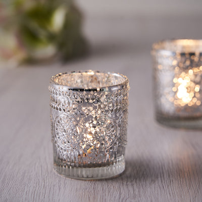 Decorative silver candle holder with intricate design and warm glow.
