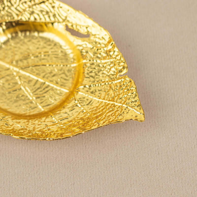 Gold leaf-shaped decorative dish on beige background.