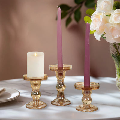 Elegant glass candlesticks with a white candle and purple taper candles.