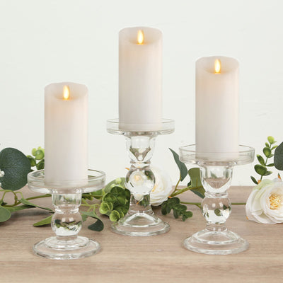 Elegant glass candle holders with white candles and greenery accents.