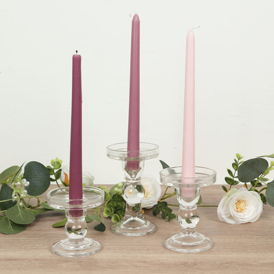 Glass candle holders with colorful candles and greenery accents.