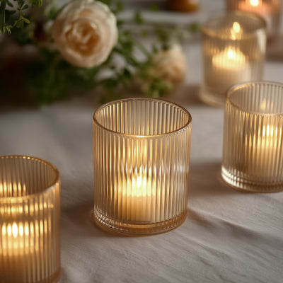 Elegant ribbed glass candle holders with warm glowing candles.