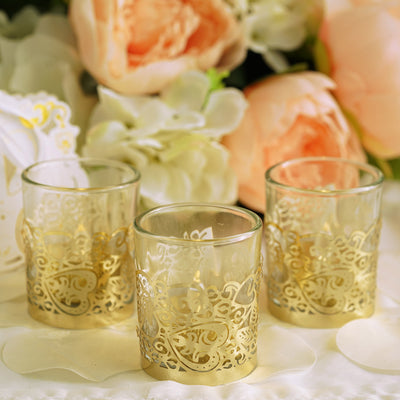 Gold-accented glass candle holders with floral background.