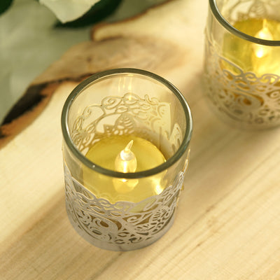 Decorative glass candle holders with intricate designs and gold candles.