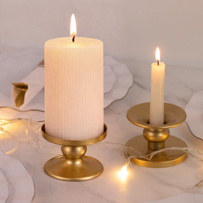 Elegant gold candle holders with white candles, softly lit with fairy lights.