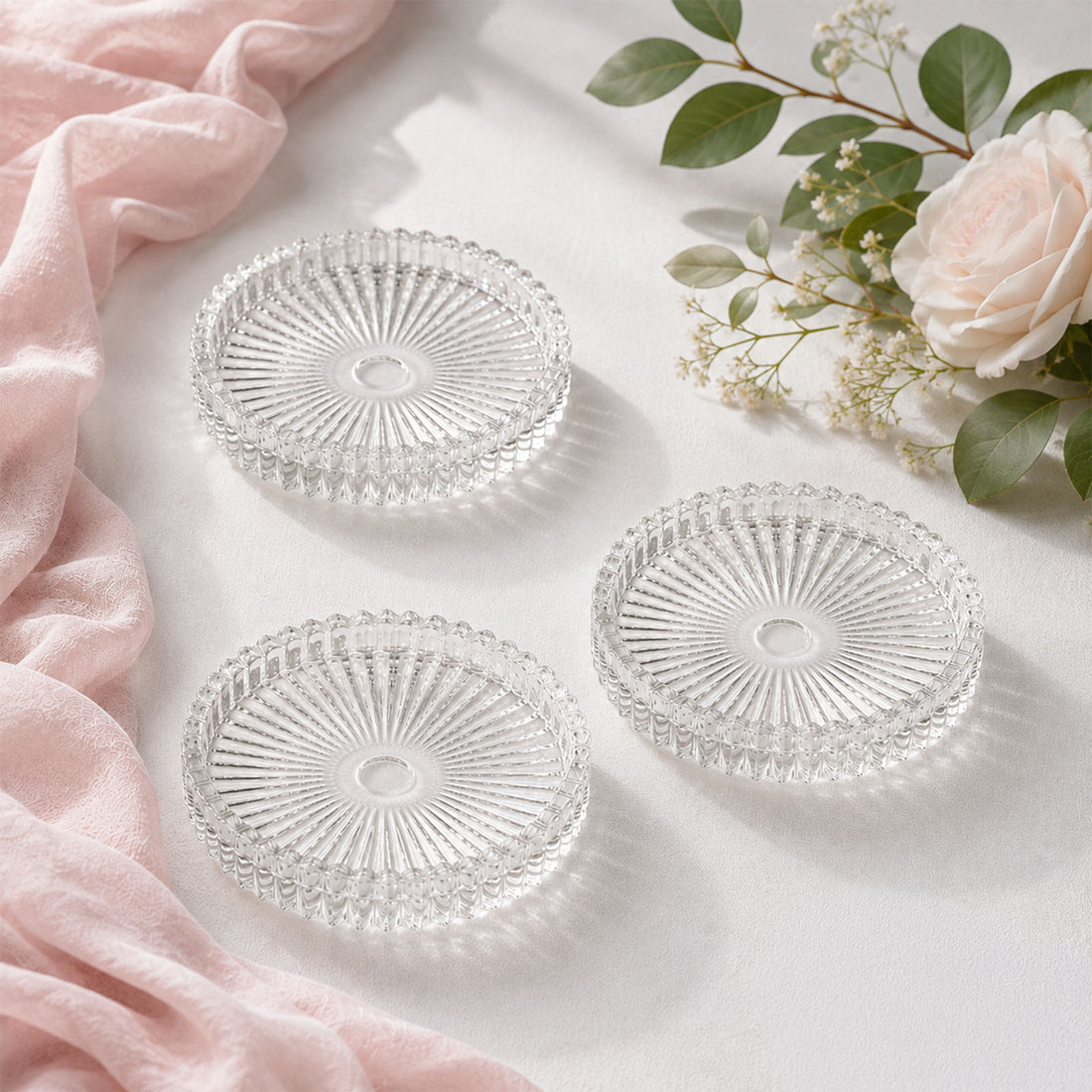 Elegant clear glass coasters with pink fabric and white roses on a soft background