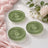 Green glass coaster set with floral styling on a soft pink and white background